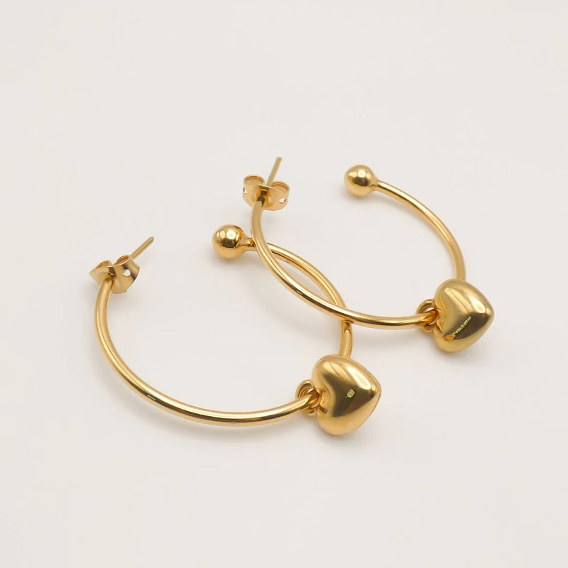 Gold hoop earrings with puffed heart charms.