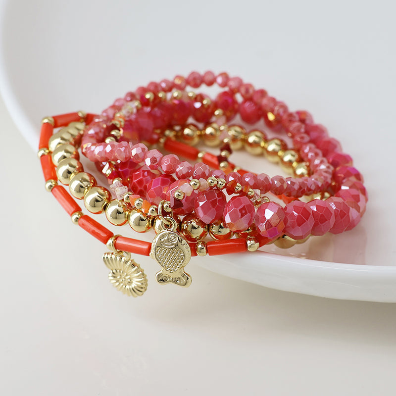 Pink and gold bead bracelet stack with fish and shell