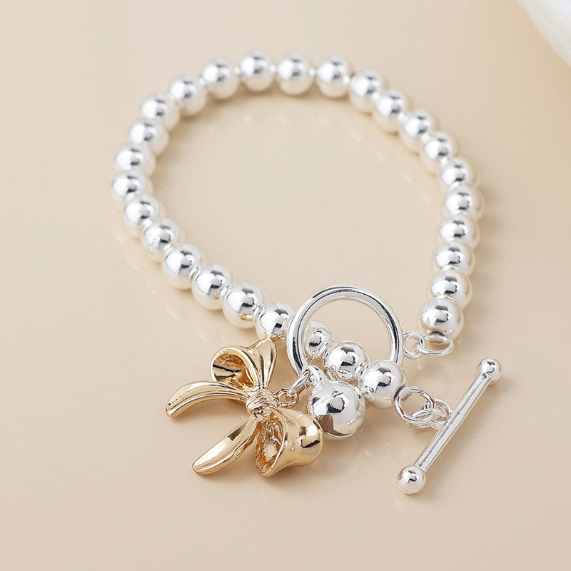 Silver plated bell and golden bow charm bracelet