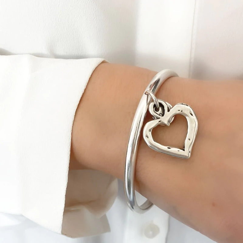 Solid bangle featuring an open hammered heart charm